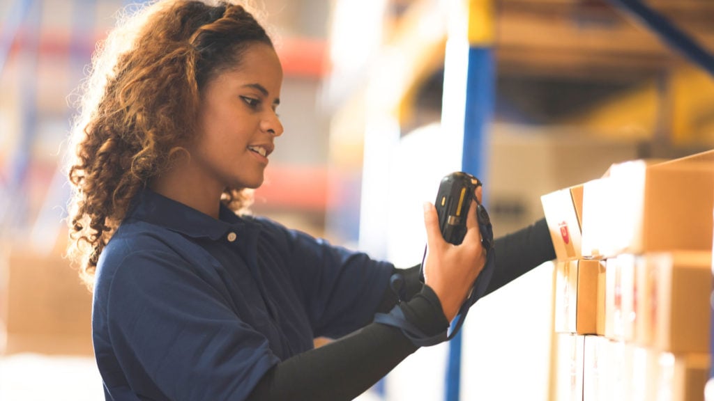 A woman checking inventory wharehouse with a barcode reader