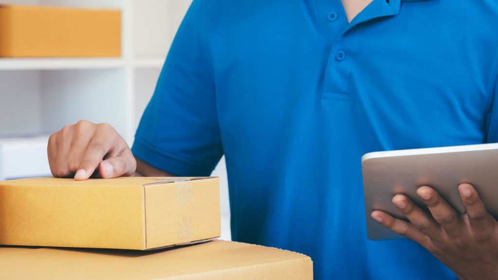 An anonymous delivery guy checking a box holding a tablet